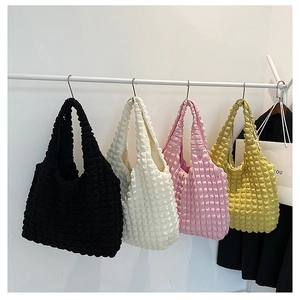 Detail of colorful bubble textured tote bags in black white pink and yellow hanging on a rack