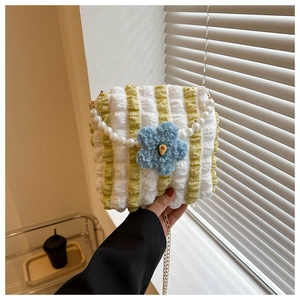 Close-up of pleated fabric tote with 3D blue flower detail and pearl handle