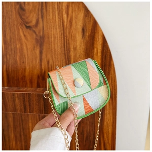 Detail of a mini geometric patchwork crossbody bag with green trim and gold chain strap