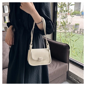 Détail d'un sac bandoulière blanc crème avec boucle carrée porté par un mannequin en noir