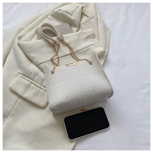 Close-up of white crocodile pattern shoulder bag with elegant gold chain strap detail