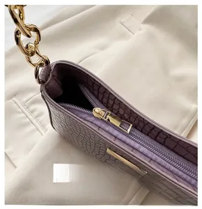 Macro detail of purple crocodile pattern leather with smooth golden metal zipper and chain