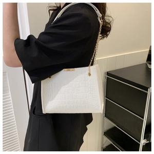 White crocodile pattern shoulder bag with gold chain strap shown on a black suit blazer