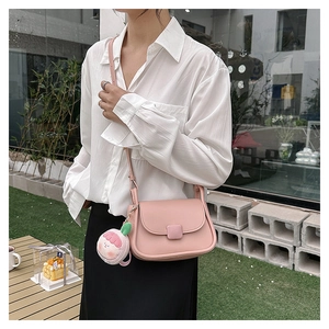 Détail du sac bandoulière rose clair avec fermoir carré et breloque en peluche rose