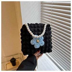 Detail of black bubble texture handbag with pearl handle and plush flower charm