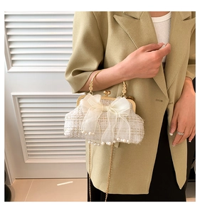 Detail of tweed evening bag with a large mesh bow, pearl charms and gold metal handle