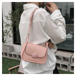 Sac bandoulière rose minimaliste porté par un mannequin dans un jardin extérieur