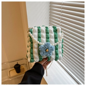 Close-up of green and white striped bag with pearl handle and plush flower charm