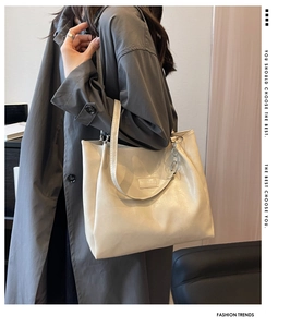 Détail du sac cabas en cuir crème avec chaîne argentée porté par un mannequin