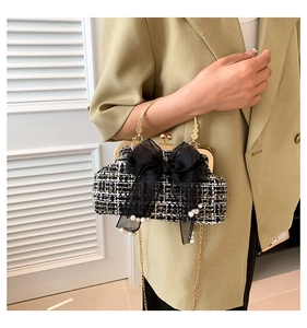 Detail of tweed chain bag with mesh bow, pearls and gold handle on green suit background