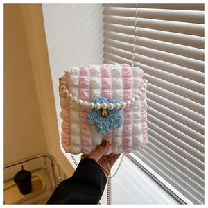 Macro view of seersucker texture bag with blue plush flower and pearl handle strap