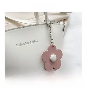 Detail of white PU leather bag with silver lettering and pink floral pendant