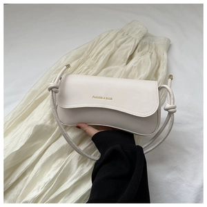Detail of cream PU leather handbag with knot strap and gold metal decorative hardware