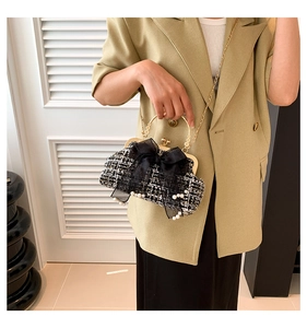 Close-up of tweed plaid bag featuring satin bow, pearls and metal ring handle