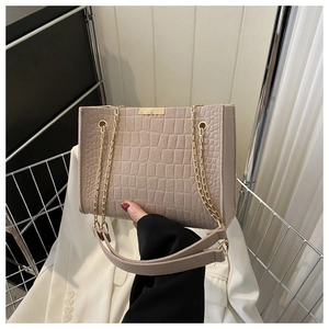 Detail of beige faux leather shoulder bag featuring crocodile pattern and gold chain strap