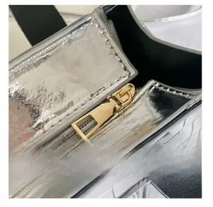 Macro shot of smooth gold zipper on silver crocodile embossed leather fashion handbag