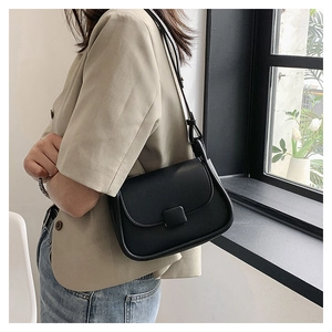 Sac à bandoulière noir en cuir PU porté par un mannequin sur un blazer décontracté