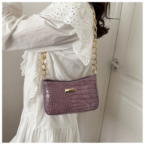 Detail of purple croc-effect shoulder bag with chunky gold chain strap on model
