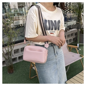 Petit sac bandoulière rose avec une large sangle colorée en situation extérieure