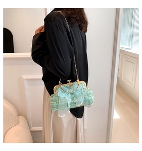 Close-up of green tweed shoulder bag with oversized blue bow and pearl drop details