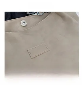 Gros plan du sac fourre-tout beige avec fermoir magnétique et détails du logo en cuir