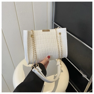 Detail shot of white crocodile embossed texture handbag with gold metal chain strap