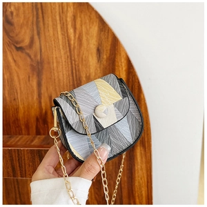Detail of a mini geometric flap bag featuring textured fabric and a light gold chain strap