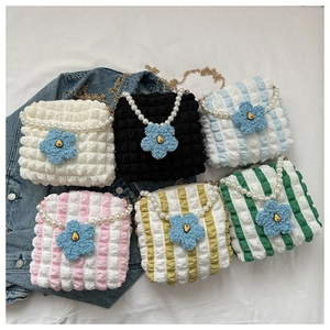 Detail showing colorful pleated bubble tote bags with floral charms and pearl straps