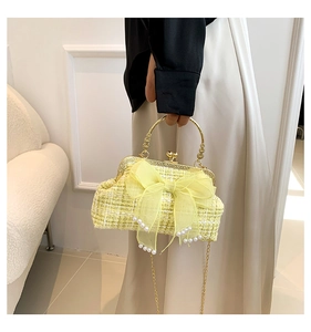 Detailed view of yellow tweed bag with sheer bow, pearl accents, and golden metal handle