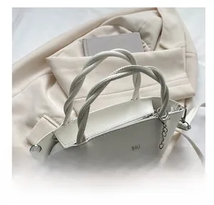 Macro view of white bucket bag featuring woven handles and floral charm detail