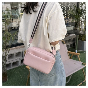 Détail du sac bandoulière rose grainé avec large sangle en tissu rayé bicolore