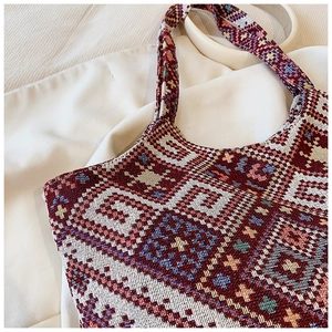 Detail showing the intricate woven geometric pattern and dual handles of the tote bag