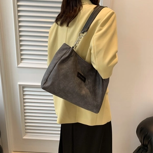 Large dark grey suede tote bag with black wide strap and silver chain detail on model