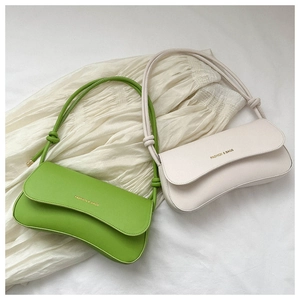 Detail view of stylish baguette bags in lime green and off-white with knot shoulder straps