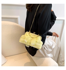 Detailed close-up of yellow tweed handbag featuring pearl bow decoration and gold chain
