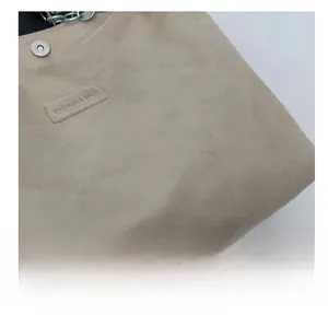 Détail d'un sac cabas beige clair avec texture cuir souple et bandoulière chaîne