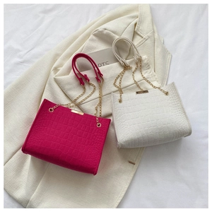 Detail of faux leather tote bags with crocodile pattern and metal chain straps
