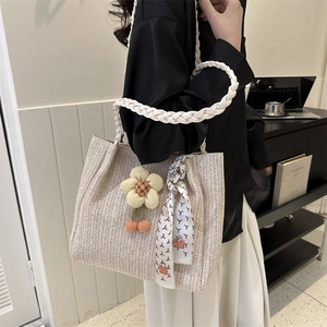 Large beige woven tote bag with floral charm and printed scarf for summer beach vacation
