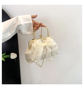 Detail of woven evening bag featuring mesh bow, pearl tassels, and gold handle hardware