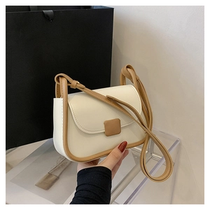 Gros plan détaillé du sac bandoulière crème avec bordure brune et fermoir carré élégant
