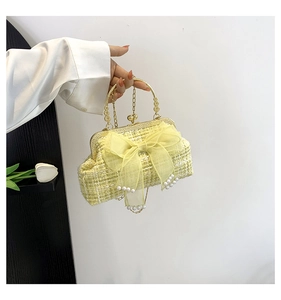 Detail of yellow tweed handbag with organza bow and pearl pendants and gold handle
