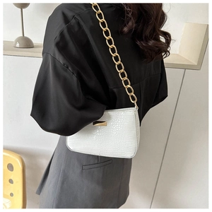Detail of white crocodile pattern baguette bag with chunky gold chain shoulder strap