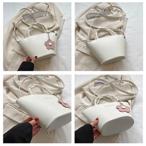 Detailed view of white bucket bag featuring woven handles and floral charm accessory