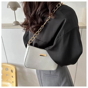 Detail of white crocodile texture underarm bag with gold chain strap on model