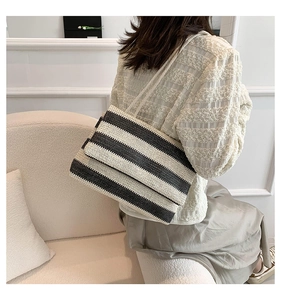 Detail of black and white striped woven tote bag with shoulder strap in stylish setting