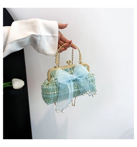 Detail of tweed handbag featuring blue organza bow and pearl fringe tassel