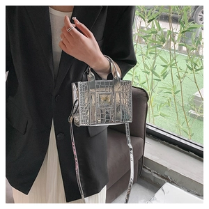 Detail of silver crocodile-embossed mini handbag with metallic finish and logo patch