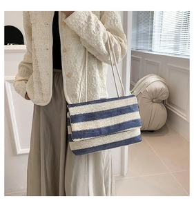 Detail of blue and white striped woven tote bag carried by model in casual outfit