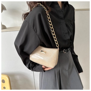 Detail of cream faux crocodile texture and chunky gold chain strap on the bag