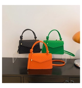 Trois sacs à bandoulière en cuir noir, vert et orange avec gaufrage en treillis et poignées